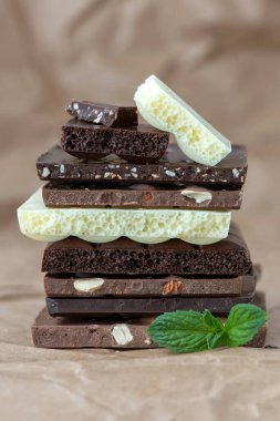 Fındık kakao tozu ve nane içeren farklı çikolata çeşitleri. Seçici odak, kahverengi kağıt kaplama arka plan.