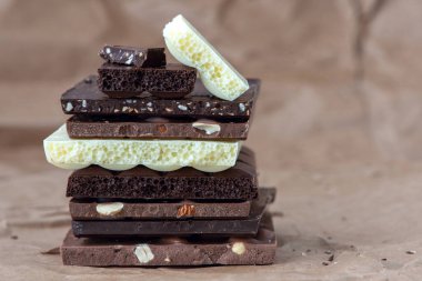 Fındık kakao tozu ve nane içeren farklı çikolata çeşitleri. Seçici odak, kahverengi kağıt kaplama arka plan.