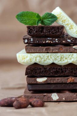 Fındık kakao tozu ve nane içeren farklı çikolata çeşitleri. Seçici odak, kahverengi kağıt kaplama arka plan.