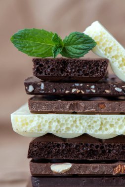 Fındık kakao tozu ve nane içeren farklı çikolata çeşitleri. Seçici odak, kahverengi kağıt kaplama arka plan.