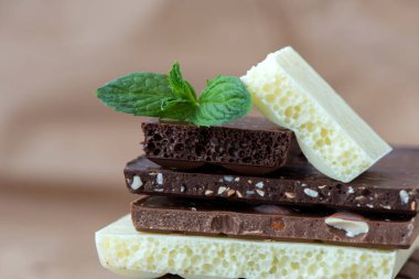 Fındık kakao tozu ve nane içeren farklı çikolata çeşitleri. Seçici odak, kahverengi kağıt kaplama arka plan.