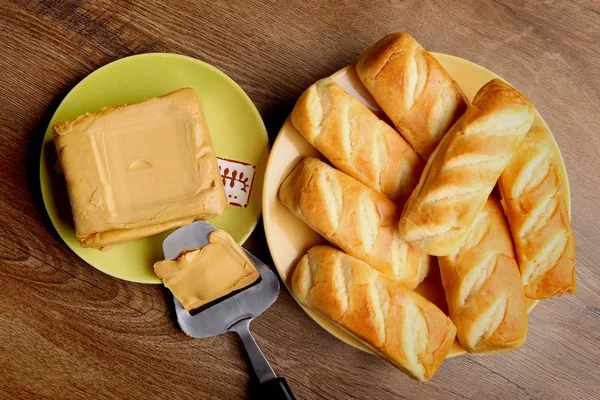 Μαλακό καφετί καραμέλα τυρί με slicer και τα ψωμάκια στον ξύλινο tabale. — Φωτογραφία Αρχείου