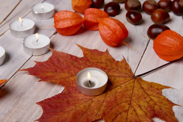 Herbstlicher Pflanzenschmuck und Kerzen auf Holztisch. — Stockfoto