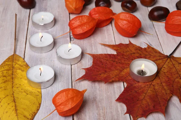 Herbstlicher Pflanzenschmuck und Kerzen auf Holztisch. — Stockfoto