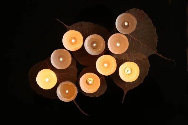 Горящие свечи с растительными украшениями в темноте — стоковое фото