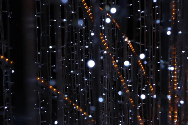 Decorative outdoor lights, blur background. Lights of cristmas garlands glowing on dark.