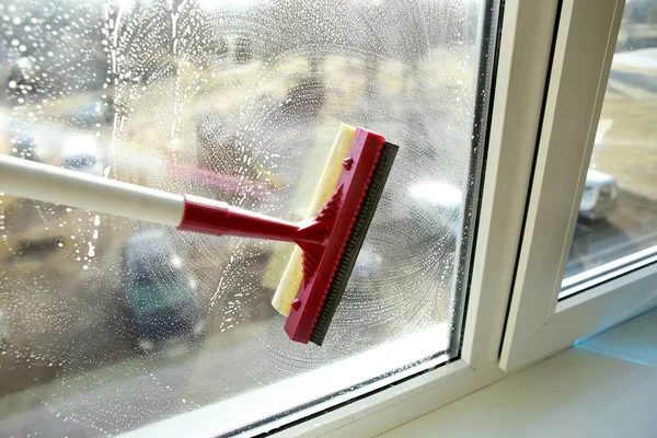 Soapy window with a squeegee cleaning the glass. Cleaning windows with a squeegee.