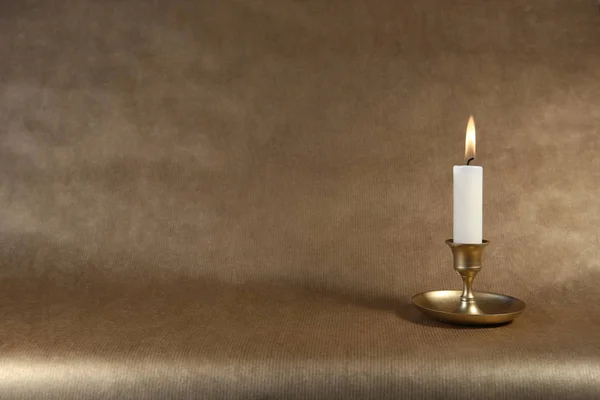 在深色金色纸背景的老式金属烛台上燃点蜡烛 并留有复制空间 — 图库照片