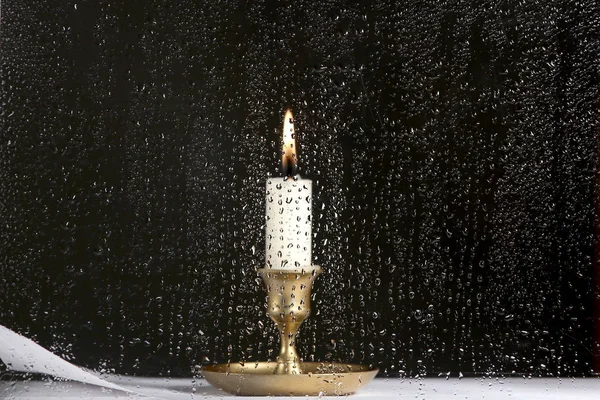 玻璃上有雨滴的烛光 在玻璃后面燃着蜡烛 玻璃杯上的水滴和老式烛台上的蜡烛 — 图库照片