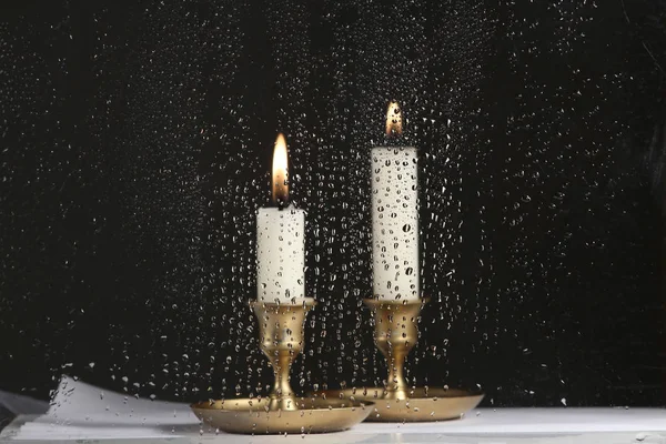 用雨滴在玻璃杯后面点燃两支蜡烛 玻璃杯上的水滴和老式烛台上的蜡烛 — 图库照片