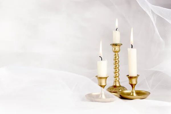 在白色抽象白色郁金香材料背景上的老式金属烛台上点燃蜡烛 — 图库照片
