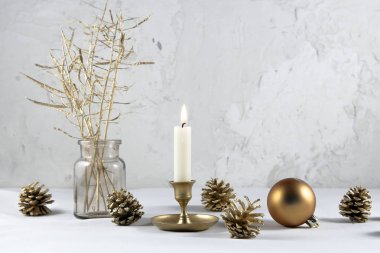 Altın Noel dekorasyonu. Mum, top, külahlar beyaz masada alçı duvara karşı kopyalama alanı
