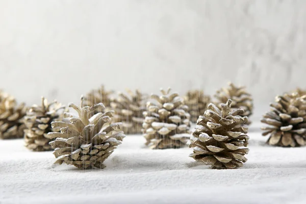 Christmas decoration cones covered snow made of icing sugar. Christmas forest concept background. Golden colored pine cones covered sugar powder