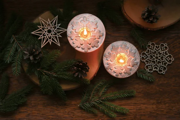 Christmas decoration, Silver candles burning on table decorated with fir branches, cones and snowflakes top view