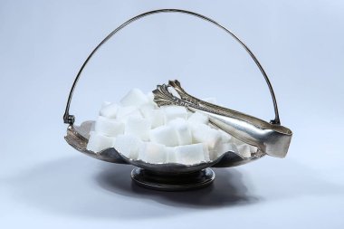 Sugar cubes in metal vintage sugar  bowl with sugar tongs