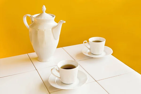 Weiße Teetassen Und Teekanne Auf Weißen Fliesen Tisch Über Gelbem — Stockfoto