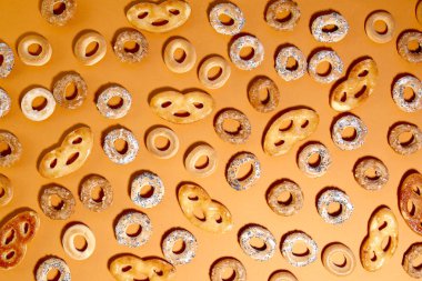 Bublik kurabiye deseni. Turuncu arka planda halka şeklinde rulo kurabiyeler