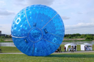 Parkta iki büyük mavi zorbing topu. Çimen tarlasında büyük plastik kabarcık.