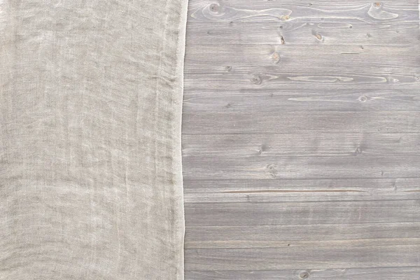 Pure washed linen cloth on grey wooden panel background with copy space. Natural washed linen fabric on wood texture surface with natural striped pattern