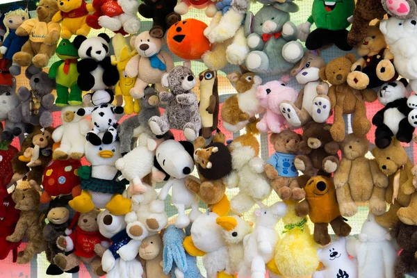 Children's colorful soft toys hanging on strings at a market.