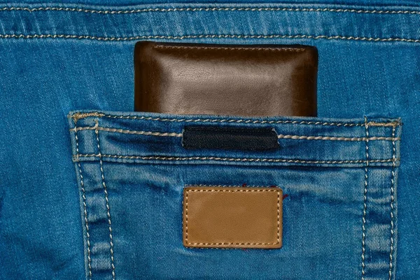 ポケットの中の茶色の革財布。財布、ジーンズ バックから半分ほど。ポケット財布ブラウンとブルー ・ ジーンズ — ストック写真