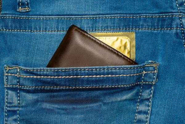 wallet in a pocket of blue jeans with a gold condom