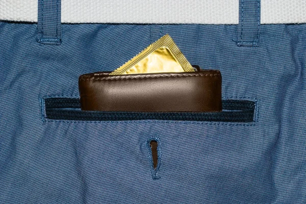 Portefeuille dans une poche de jeans bleus avec un préservatif en or — Photo