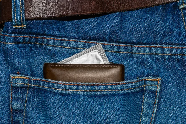 wallet in a pocket of blue jeans with silver condom
