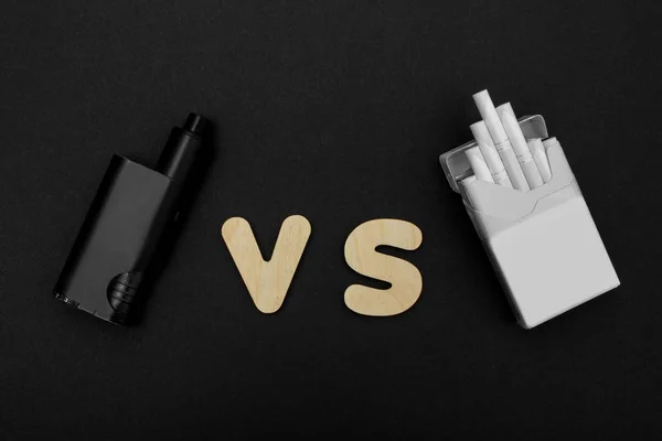 Cigarettes against Vape. Electronic cigarette over a dark background. Popular devices of year - modern vaping device. — Stock Photo, Image