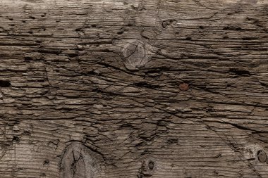 Bıçaktan derin kesikler ve balta darbeleriyle çok eski ve hırpalanmış bir ahşap arka plan. Böcekler tarafından tahrip edilmiş ağaç. Güneşin altında bir tahta, kar, yağmur ve rüzgar. Yaşlanmış ağaç