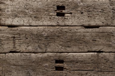 Bıçaktan derin kesikler ve balta darbeleriyle çok eski ve hırpalanmış bir ahşap arka plan. Böcekler tarafından tahrip edilmiş ağaç. Güneşin altında bir tahta, kar, yağmur ve rüzgar. Yaşlanmış ağaç