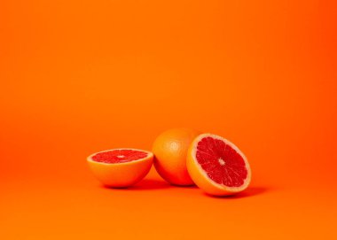 Olgun greyfurtlar. tüm greyfurt ve turuncu arka planda dilimlenmiş.