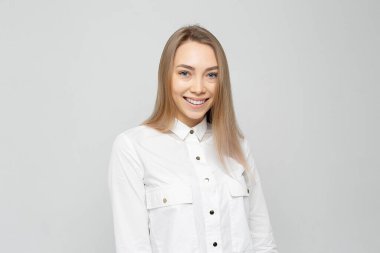 Güzel genç kadın portresi. Beyaz-gri tişörtlü, gülümseyen sarışın güzel bir kızın portresi..