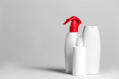 Açık arkaplanda beyaz ve gri kaplarda kozmetik ürünleri seti.