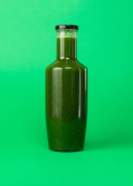 Yeşil arka planda izole edilmiş plastik bir şişede taze kereviz ıspanak suyu. Sağlıklı yeme Detox meyve suyu diyeti