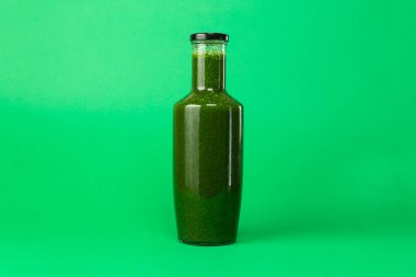 Yeşil arka planda izole edilmiş plastik bir şişede taze kereviz ıspanak suyu. Sağlıklı yeme Detox meyve suyu diyeti