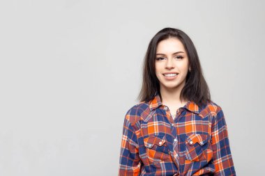 Güzel genç kadın portresi. Beyaz-gri bir gömlekle gülümseyen güzel bir esmerin portresi.