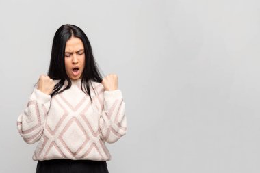 Beyaz, sıcak, kış süveteri içinde genç, güzel bir esmer portre yumruklarla el ele tutuşuyor, agresif yüz ifadesi takınıyor..