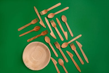 Yeşil arka planda bambu ağacından yapılmış çevre dostu tek kullanımlık aletler. Örtülü kaşıklar, çatal, bıçaklar, bambu kaseleri.