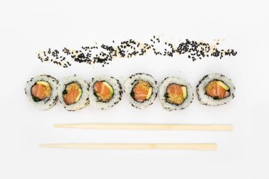 Japon mutfağı. Maki suşisi. Beyaz arka planda izole edilmiş. Suşi ruloları beyaz arka planda yatar, üst manzarada, onların yanında Japon bambu çubukları bulunur. Japon restoranının menüsü için kavramsal fikir