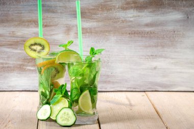 İki ferahlatıcı yaz kokteyli limon ve nane, kivi ve salatalık Sarı tahta bir masada