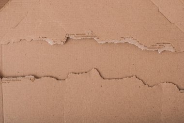 Yırtık kenarlı eski desenli karton çarşaf. Kahverengi karton koparılmış. Karton desen. Yırtık pırtık bir karton yaprak bir karton yaprağın üzerinde yatıyor..