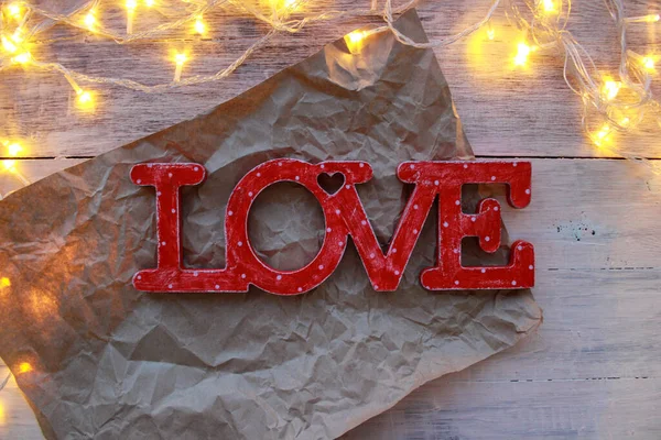 Wooden word LOVE red in white polka dots. Shabby chic, rustic. Light background with lights, bokeh.