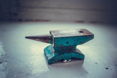 Ahşap masada küçük mavi demir örs