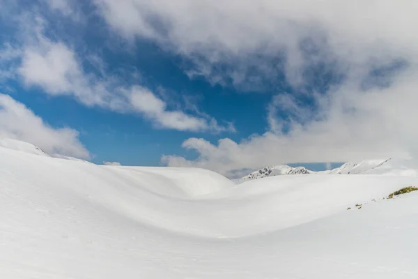 Snö kullar mot klar blå himmel — Stockfoto