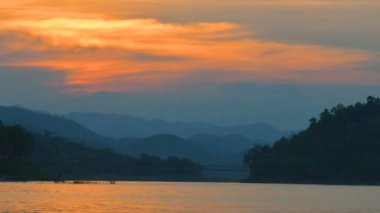 Güzel gün batımı ve Tayland arka plan olarak dağ silsilesi ile göl üzerinde dramatik gökyüzü.