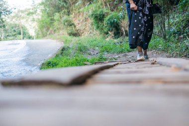 tek başına ormana ahşap köprü üzerinde yürüyen yalnız kadın