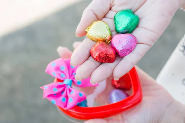 Hand of a young woman holding a chocolate heart shaped — Stock Photo, Image