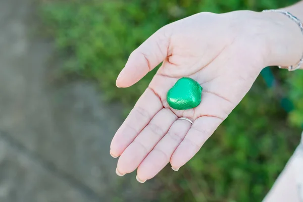 Hand of a young woman holding a chocolate heart shaped — Stock Photo, Image