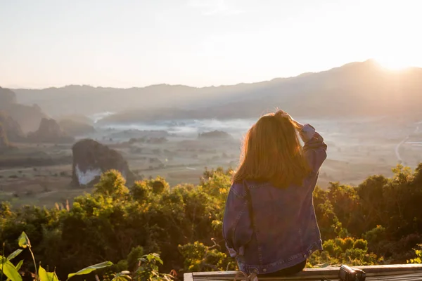Junge Frau beobachtet Sonnenaufgang hoch im Berg bei phu lung ka — Stockfoto